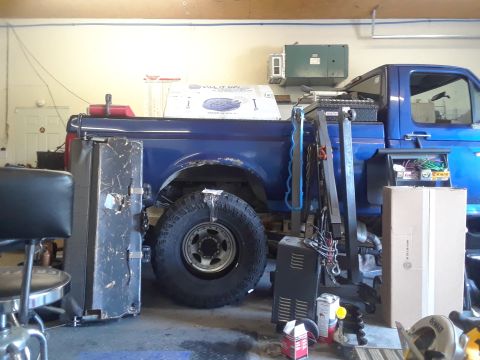 1996 Ford F-350 - Side view of a blue pickup truck's rear section, a large off-road tire and the truck bed.