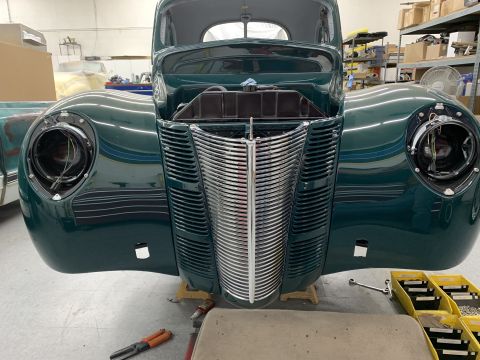 1940 Ford Coupe - The distinctive grille and rounded fenders of a 1940 Ford Coupe are shown in a workshop setting.