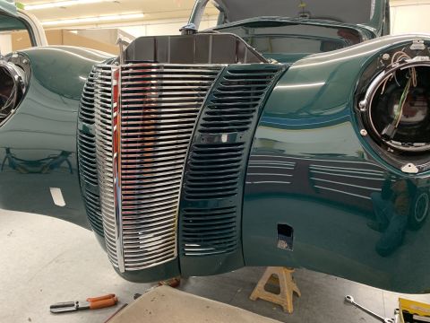 1940 Ford Coupe - The front end of a green 1940 Ford Coupe is visible, showing its distinctive grille and headlight housings.