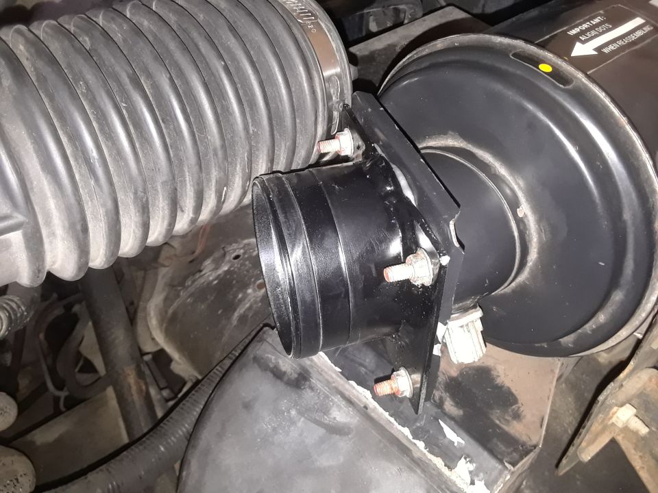 Close-up of engine air intake hose and housing. Some text is visible on the housing