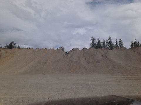 1995 Ford Bronco - A white SUV navigates a challenging dirt incline, with trees visible on the crest of the hill.
