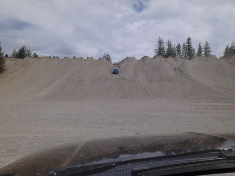 1995 Ford Bronco - A blue SUV navigates a steep sandy incline at an off-road park.