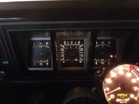 1978 Ford Bronco - Close-up of a vehicle's illuminated dashboard gauges, including fuel, oil, speed, voltage, and temperature indicators.