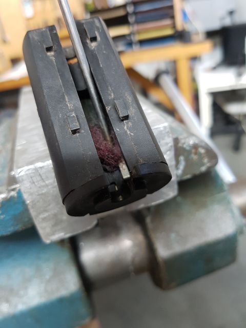 1978 Ford Bronco - A part is being cleaned while secured in a vise with a brush tool.