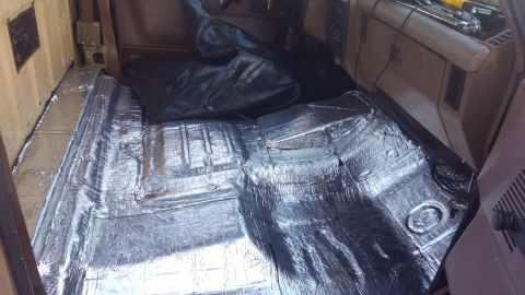 1990 Ford F-250 - Sound deadening material being installed on the floor of a vehicle interior.