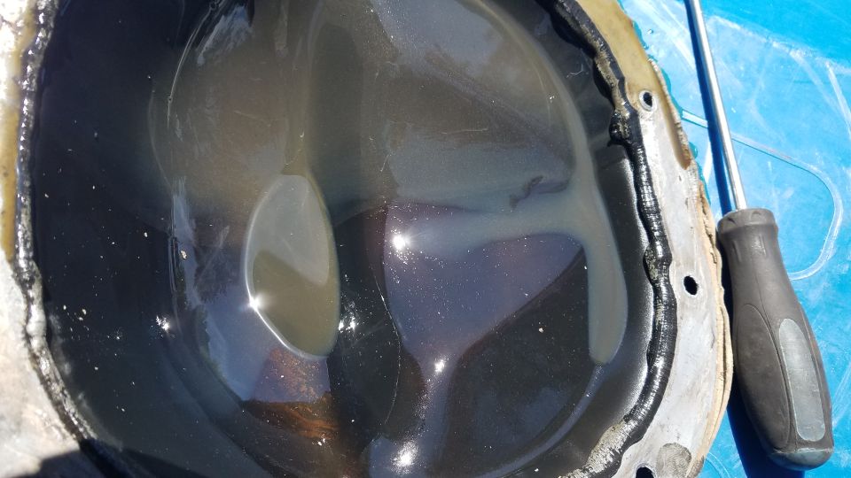 Differential cover with dark fluid and a screwdriver nearby