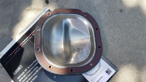 1985 Ford Bronco - Differential cover and gasket shown on a surface, with product features printed on paper underneath.
