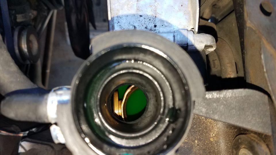 Radiator cap opening showing green coolant inside. SuperMotors.net logo visible