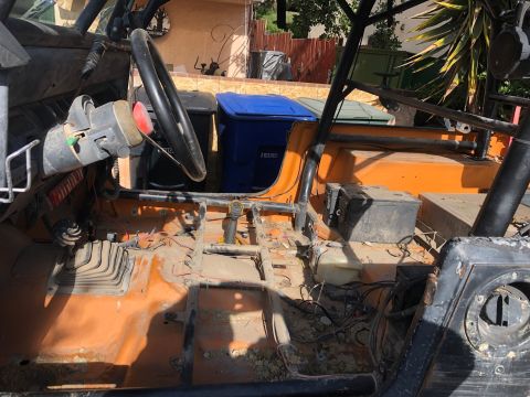 1992 Jeep Wrangler - The interior of a stripped-down off-road vehicle shows its orange floor, roll cage, and steering column.
