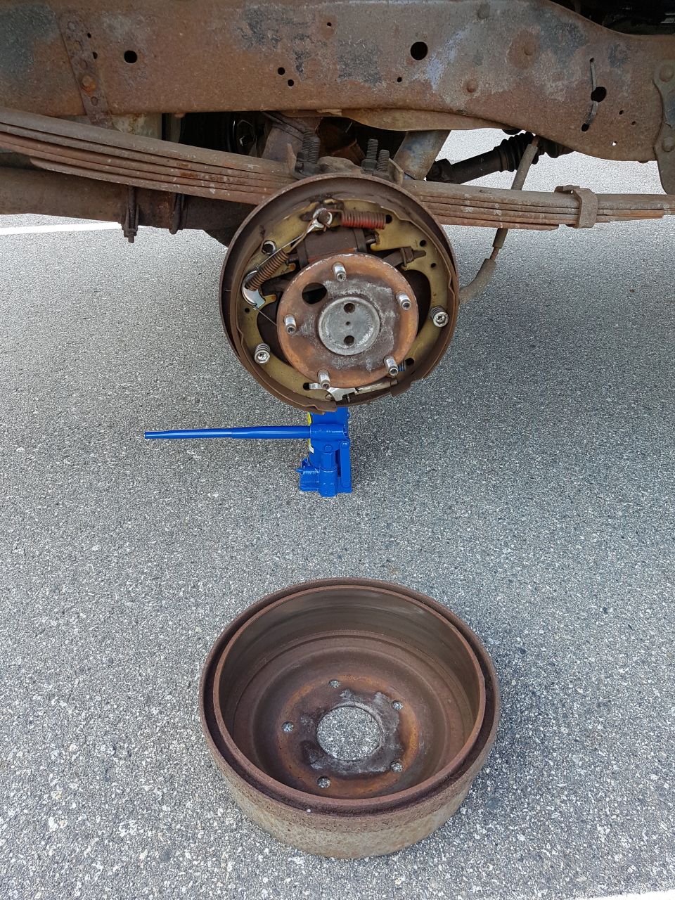 Rear drum brake assembly and removed drum on asphalt