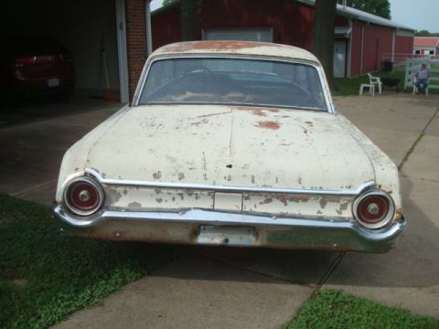 1962 Ford Galaxie - This old Ford sedan is parked outside a red barn, showing significant wear and tear.