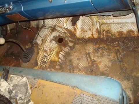 1962 Ford Galaxie - The interior floor shows significant rust and damage, with a floor shifter and blue seat trim visible.