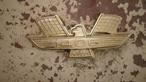 1962 Ford Galaxie - Close-up of a '406' emblem, likely a car part, set against a heavily weathered background.