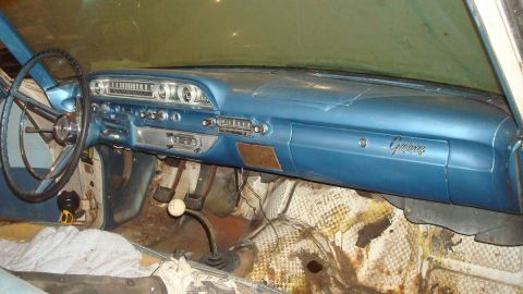 1962 Ford Galaxie - The dashboard and interior of a vintage car, showing the steering wheel, radio, and gear shift.