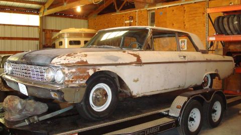 1962 Ford Galaxie - This 1962 Ford Galaxie is seen on a trailer, showing its front three-quarter view with significant rust and peeling paint.