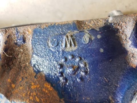 1963 Ford Fairlane - A close-up view of a rusty, blue-painted metal component with visible casting marks and numbers.