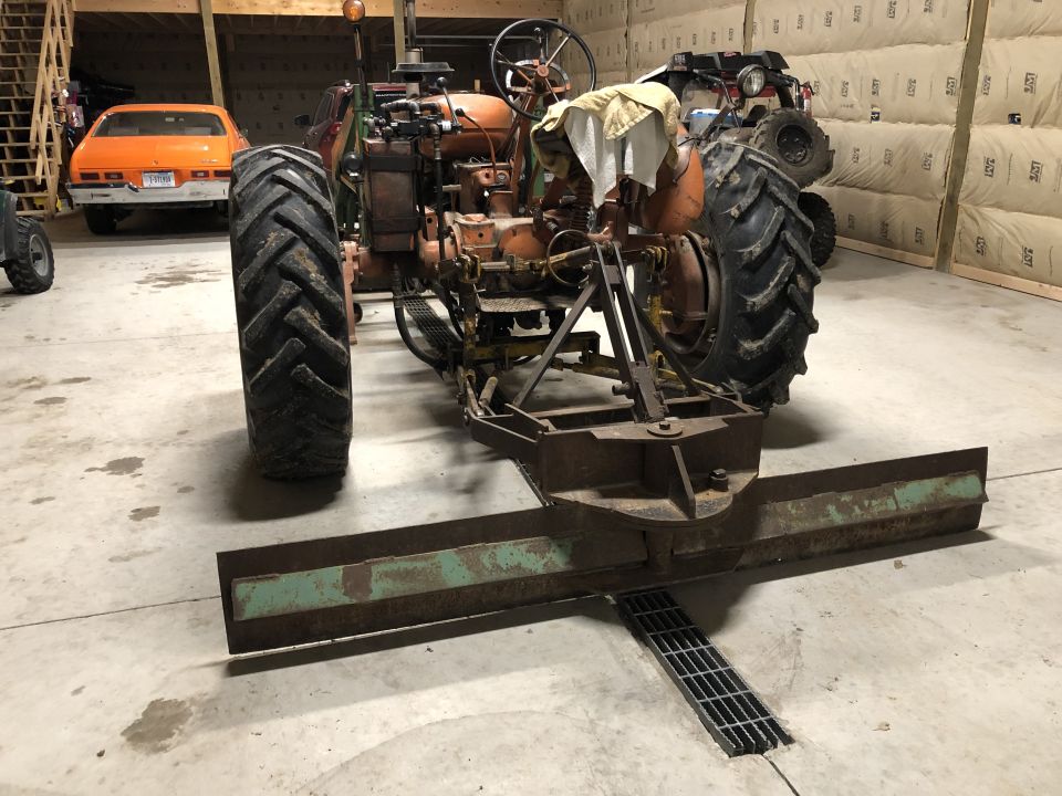 Tractor with rear blade attachment, orange car in background