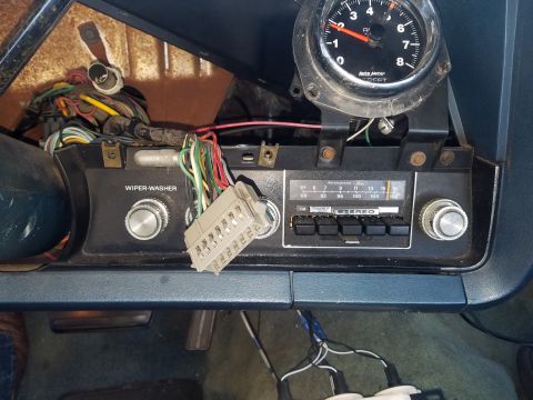 1977 Ford Ranchero - The interior of a vehicle displays a radio, wiper-washer controls, and an aftermarket tachometer with exposed wiring.