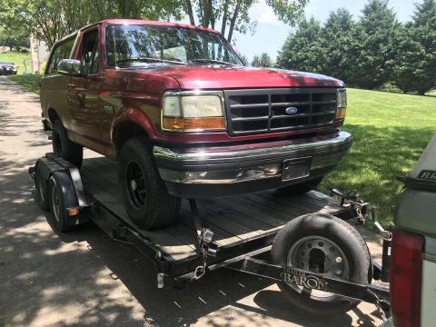 1994 Ford Bronco - A red 1994 Ford Bronco is loaded onto a trailer for transport.