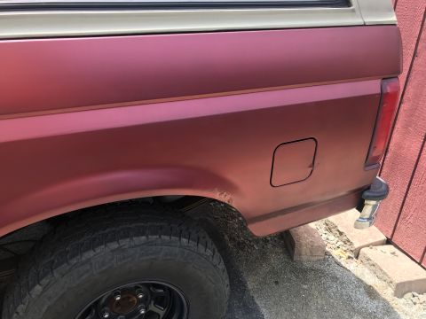 1994 Ford Bronco - Rear view of a red Ford Bronco showing the quarter panel, fuel door, and a rust spot near the wheel well.