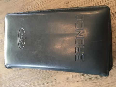 1994 Ford Bronco - This is a black owner's manual case for a Ford Bronco, the Ford logo and 'BRONCO' embossed on the cover.