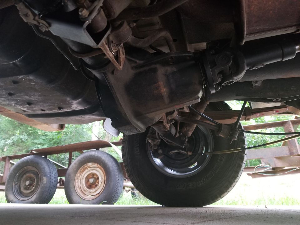 Undercarriage view of a vehicle, showing the differential and suspension, with a trailer and its wheels visible below