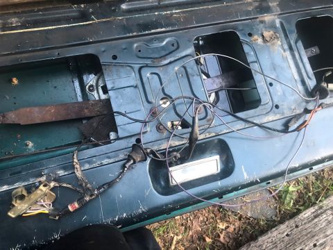 1995 Ford Bronco - Close-up of a vehicle's tailgate interior, revealing exposed wiring and mechanical parts.