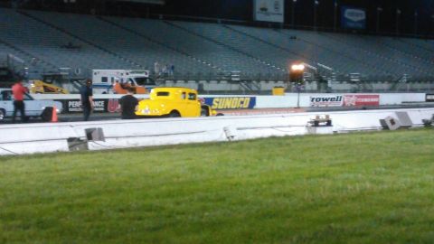 2017 Ford Mustang - A yellow hot rod is positioned on a drag strip with grandstands in the background.