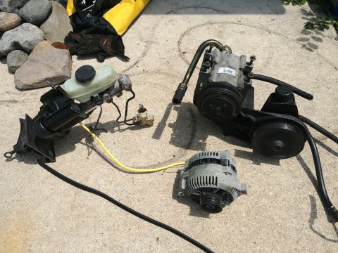 1977 Ford Ranchero - Vehicle parts including brake master cylinder, power steering pump, and alternator are on the ground.