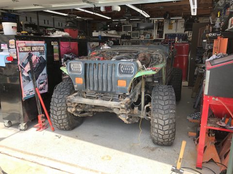 1992 Jeep Wrangler - A Jeep Wrangler is parked in a garage with its hood open and appears to be undergoing some work.