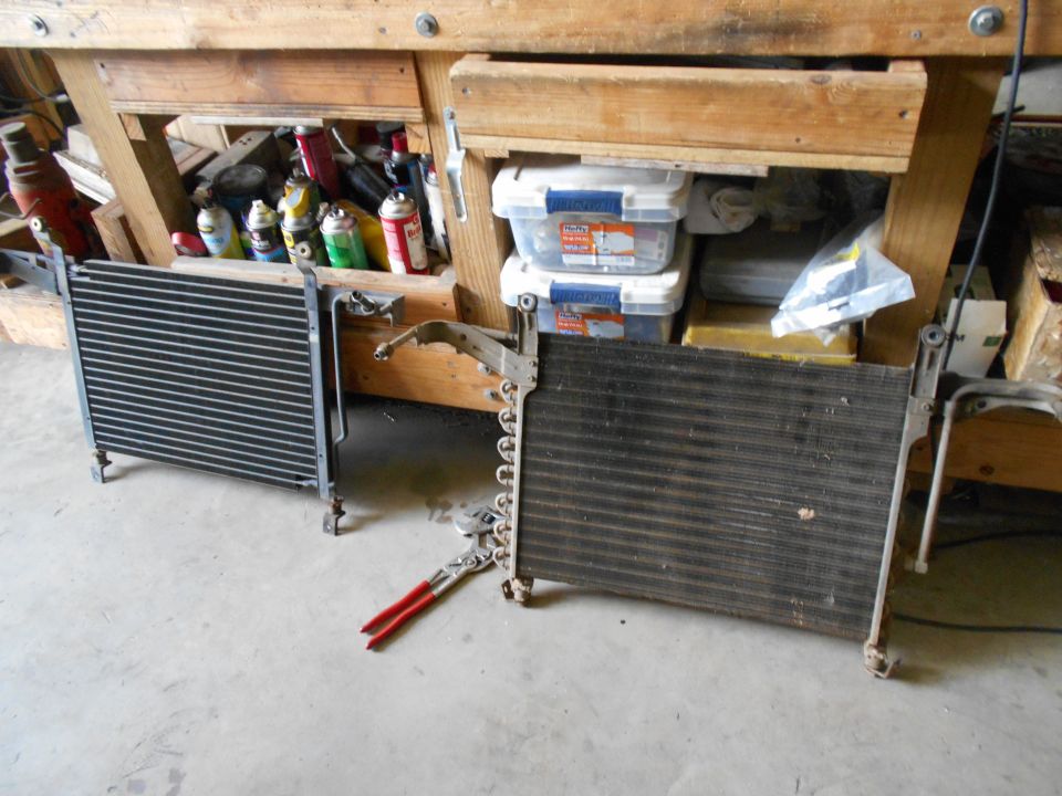 Two car radiators or AC condensers on a concrete floor, one on the left and one on the right, with red-handled pliers between them