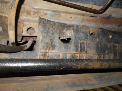 1992 Ford Bronco - Close-up of the undercarriage reveals various metal and plastic components, some showing signs of rust.