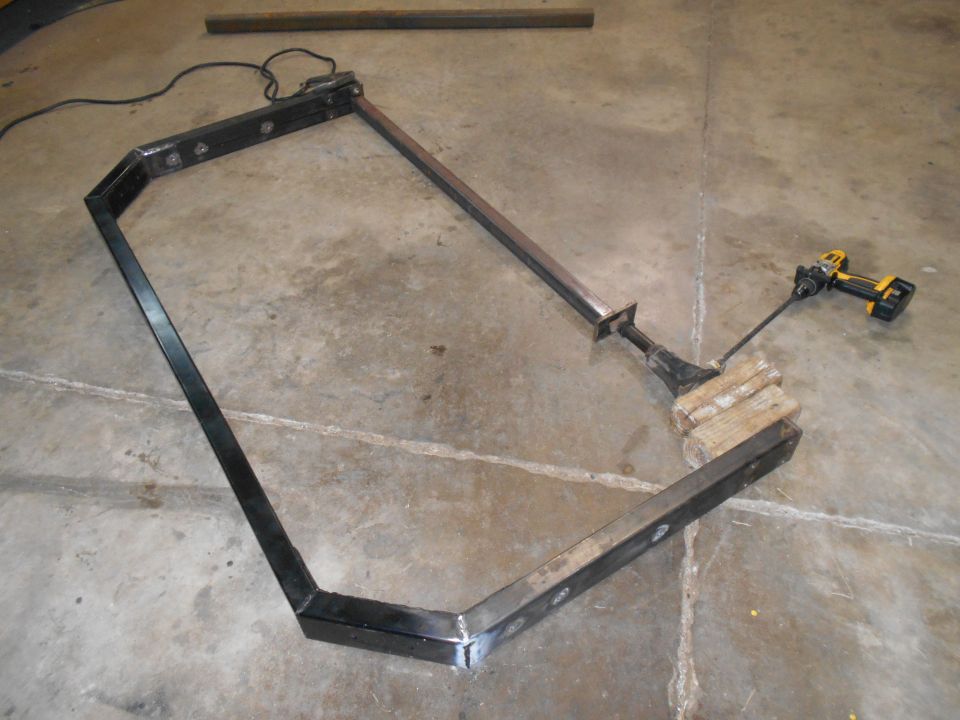 fabricated metal frame with a drill attached to a wooden block