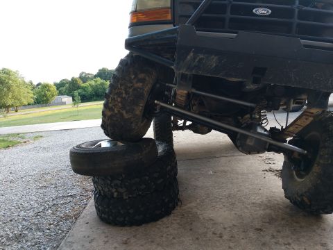 1995 Ford Bronco - A modified Ford Bronco sits with its front tire resting on a stack of other tires.