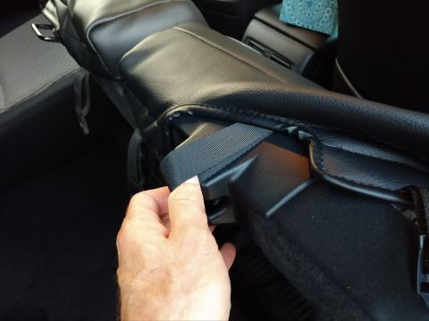 2018 Toyota 4Runner - Close-up of a hand installing a black seat cover onto a car seat, showing the attachment mechanism.