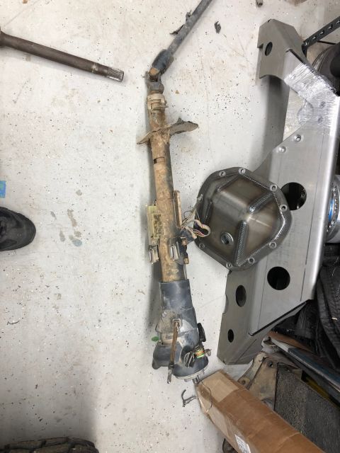 1992 Jeep Wrangler - A disassembled steering column and a new differential cover are shown on a concrete floor, likely in a garage or workshop.