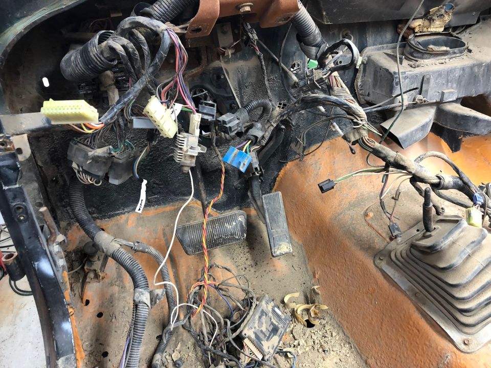 Disassembled vehicle dashboard wiring harness with exposed wires and connectors