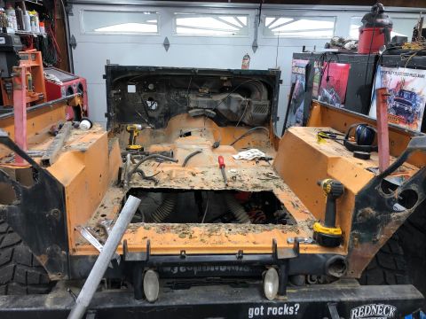 1992 Jeep Wrangler - The interior of an orange Jeep Wrangler is disassembled, revealing its internal components and floor pan.
