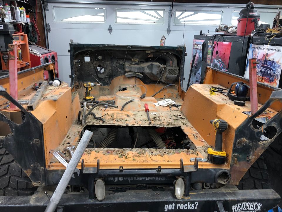 Orange Jeep Wrangler interior stripped down, showing floor pan and dashboard components