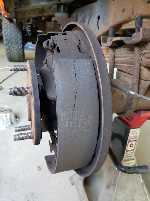 1978 Ford Bronco - Close-up of a cracked brake shoe within a drum brake assembly.