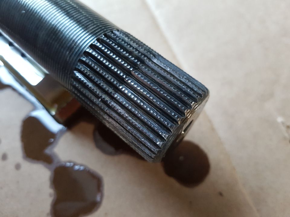 Splined shaft end with oil drips on a surface