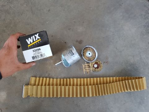 1978 Ford Bronco - Disassembled fuel filters and filter material are laid out on a concrete surface.
