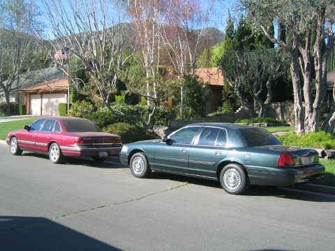 1992 Ford Crown Victoria - A green 1992 Ford Crown Victoria is parked on a residential street next to a red sedan.