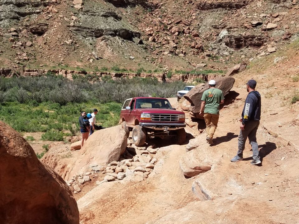 1995 Ford Bronco navigating a rocky trail with people watching