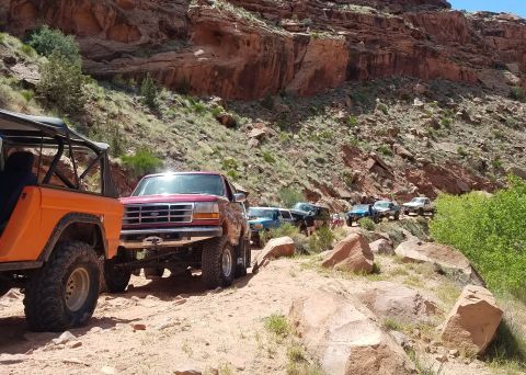 1995 Ford Bronco - A convoy of off-road vehicles, including a red 1995 Ford Bronco, navigates a , rocky terrain.