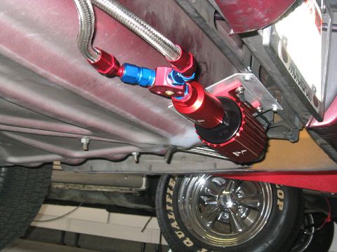 1992 Ford Crown Victoria - An aftermarket fuel filter assembly is mounted to the undercarriage of a vehicle, with a chrome wheel visible below.