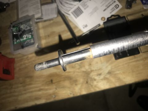 1994 Ford Bronco - A close-up view of a metal rod with a black handle, resting on a wooden surface. The rod appears to be a tool or part of a larger assembly,…