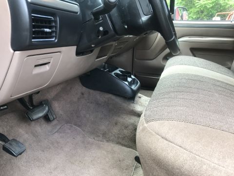 1994 Ford Bronco - Interior view of a 1990s Ford Bronco showing the driver's side dashboard, steering wheel, and seat. Visible details include the fuse panel…