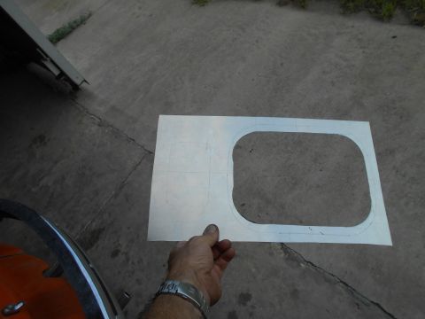 1992 Ford Bronco - A hand holds a paper template with a cut-out shape, likely for a vehicle modification, over a concrete surface.