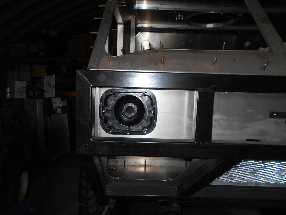 Close-up of a black circular part installed in a metal frame on a custom vehicle.